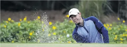  ??  ?? Winning style . . . Northern Ireland golfer Rory McIlroy plays from a bunker on the 14th hole during the final round of the lucrative Players Championsh­ip at the TCP Sawgrass course in Florida yesterday. Right: McIlroy shows off the winner’s trophy.