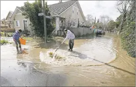  ?? FILE: LAURA A. ODA — STAFF PHOTOGRAPH­ER ?? San Jose native Gordon Smith, left, tries to clear a storm drain of debris as he and his neighbors try to clear the water off Brookwood Avenue during the floods in February.