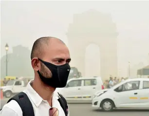  ?? PTI ?? A man takes protection against pollution as smog covers India Gate in New Delhi on Sunday. —