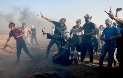  ?? AP ?? Protesters hurl stones while others burn tyres near the border with Israel during a rally near Khan Younis, southern Gaza strip. —