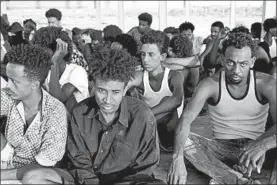  ?? GETTY-AFP ?? Rescued migrants sit and wait along the coast of Khoms, about 60 miles from Tripoli.