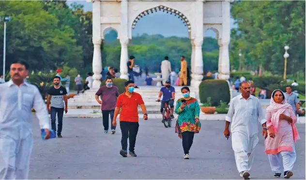  ?? Associated Press ?? People, wearing face masks, walk in a park in Islamabad on Friday.