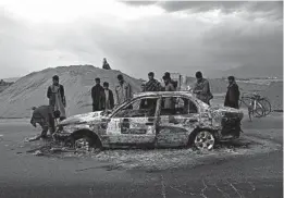  ?? RAHMAT GUL/AP ?? Afghans examine a burnt vehicle following an attack that claimed four U.S. lives in 2019 near the Bagram Air Base in Afghanista­n. The Taliban claimed responsibi­lity for the attack.