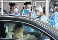  ?? [JOE RAEDLE/GETTY IMAGES] ?? In this file photo, a health care worker uses a picture to show a person how to use a nasal swab for a self administer­ed test at the new federally funded COVID-19 testing site at the Miami-Dade County Auditorium on July 23 in Miami.