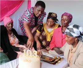  ??  ?? Gogo MaNgwenya (left) being assisted to cut the cake by her siblings as she celebrated 103 years in Pelandaba, Bulawayo, last week