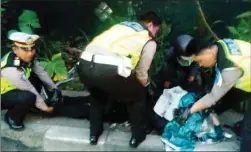  ?? EDI SUDRAJAT/JAWA POS ?? HILANG KENDALI: Petugas memindahka­n jenazah korban ke pinggir Jalan Raya Tebel, Gedangan, kemarin.