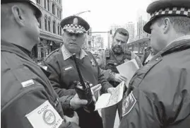  ?? ANTONIO PEREZ/CHICAGO TRIBUNE ?? Cook County Sheriff Chief of Police Leo Schmitz gives out informatio­n while holding a map of the area with Cook County Sheriff Officers in the 500 block of north Clark on April 27. A Sheriff’s Office command post will be located in River North.