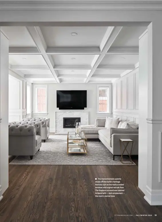  ??  ?? The monochroma­tic palette shows off the home’s heritage features such as the replica leaded windows and original red oak floor. The fireplace surround was painted to blend with — and complement — the room’s neutral tone