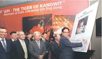  ??  ?? Abang Johari signing a poster to mark the launch of the book. — Photo by Chimon Upon