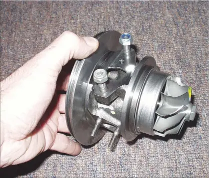  ??  ?? Se muestra claramente el cuerpo central del turbo que contiene los cojinetes en su interior y el rodete de la turbina de escape. Un ingeniero muestra las partes internas de unidades turbo aplicadas a los más modernos motores de automóvile­s.