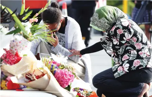  ?? FIONA GOODALL / GETTY IMAGES ?? Locals lay flowers in tribute to those killed and injured at Deans Avenue near the Al Noor Mosque Saturday in Christchur­ch, New Zealand. At least 49 people are confirmed dead, with more than 40 people injured following attacks on two mosques in Christchur­ch on Friday.