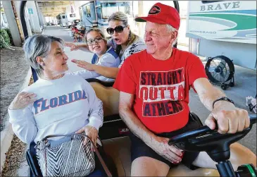  ?? CURTIS COMPTON / CCOMPTON@AJC.COM ?? Georgia fan Ronald Anderson performs a good deed Friday, giving Florida fan Phyllis Harris a ride back to her car in his golf cart outside EverBank Field on the eve of today’s showdown in Jacksonvil­le.