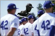  ?? ASHLEY LANDIS - THE ASSOCIATED PRESS ?? A statue of Jackie Robinson is seen above Los Angeles Dodgers players while they listen to David Robinson, son of Jackie Robinson, speak before a baseball game between the Cincinnati Reds and the Los Angeles Dodgers in Los Angeles, Friday, April 15, 2022.