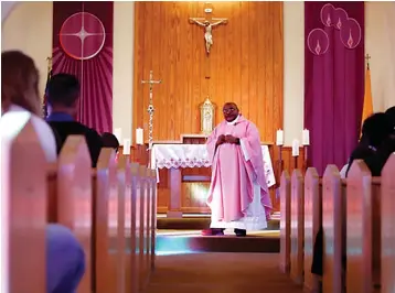  ?? AP Photo/Jessie Wardarski ?? ■ The Rev. Athanasius Abanulo celebrates Mass on Dec. 12, 2021, at Holy Family Catholic Church in Lanett, Ala. Originally from Nigeria, Abanulo is one of numerous internatio­nal clergy helping ease a U.S. priest shortage by serving in Catholic dioceses across the country.