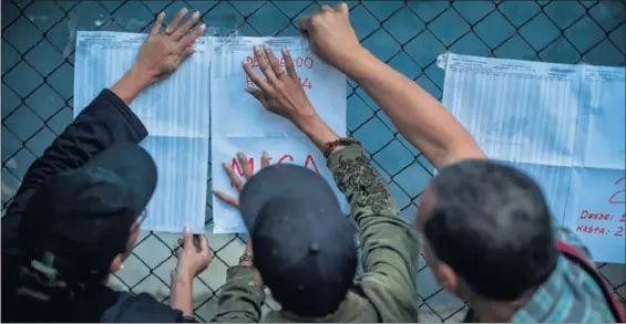  ?? / MIGUEL GUTIÉRREZ (EFE) ?? Tres ciudadanos buscan su mesa electoral para votar en los comicios municipale­s el domingo en Caracas.