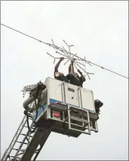  ?? / Kevin Myrick ?? Holiday decoration­s were going up in downtown Cedartown this past week as firefighte­rs blocked off the roadway to string snowflakes above Main Street.