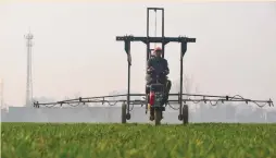  ?? (Reuters) ?? A FARMER sprays pesticide with a machinery in a wheat field in Wangdu, China. The focus this week could be on what companies say about consumer spending, the impact of the US-China trade war on corporate results and what earnings might look like in the second half of the year.
