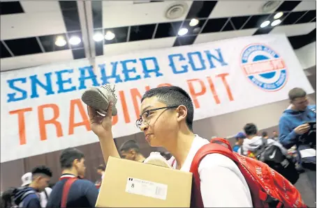  ?? PHOTOS BY ANDA CHU — STAFF PHOTOGRAPH­ER ?? Ronin Celio, 17, of South San Francisco, holds up a 2015Adidas Yeezy Moonrocks sneaker as he looks for a buyer in the “trading pit” during Sneaker Con at the Santa Clara Convention Center on Saturday.