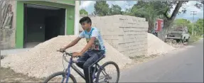  ??  ?? Un joven ciclista pasa junto a material de construcci­ón en una casa para un apoyo de acción de vivienda