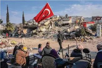  ?? Bernat Armangue/Associated Press ?? A family sits next to a collapsed building as they wait for the bodies of their relatives to be recovered from under the rubble in Antakya, Turkey, on Saturday. Rescue teams using thermal cameras to locate signs of life are continuing to pull survivors out of mounds of rubble, five days after a major earthquake struck a sprawling border region of Turkey and Syria.