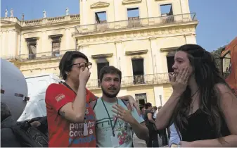  ?? Silvia Izquierdo / Associated Press ?? National Museum employees console each other outside the burned structure in Rio de Janeiro. The museum held Latin America’s largest archive of artifacts, objects and documents.