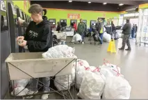  ?? Associated Press photo ?? Portland resident Sarah Marshall drops empty water bottles and soda cans at a BottleDrop redemption centre in Portland, Ore., on Saturday, the first day the per-bottle recycling refund rate jumped to 10 cents.