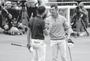  ?? Andrew Redington/Getty Images ?? Norway’s Viktor Hovland, left, and Rory McIlroy of Northern Ireland shake hands on No. 18 during the third round of the British Open. Both shot 6-under 66 and are tied for the lead at 16-under.