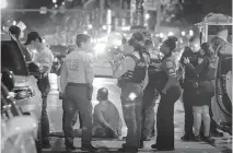  ?? ALIE SKOWRONSKI askowronsk­i@miamiheral­d.com ?? A man sits on a ground handcuffed Sunday night after witnesses say he had a knife. The detention came after a pair of deadly shootings over the weekend rocked this year’s spring break on Miami Beach.