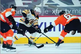  ?? Associated Press photo ?? Boston Bruins’ Brad Marchand battles for the puck against Philadelph­ia Flyers’ Justin Braun (61) and Michael Raffl (12) during the first period of an NHL hockey game, Friday in Philadelph­ia.