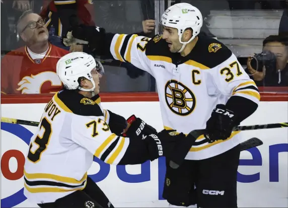  ?? JEFF MCINTOSH — THE CANADIAN PRESS VIA AP ?? Boston Bruins defenceman Charlie McAvoy, left, celebrates his overtime goal against the Calgary Flames with forward Patrice Bergeron on Tuesday night in Calgary.