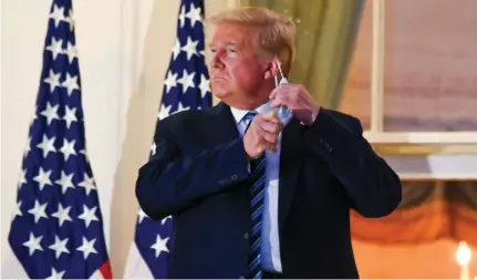  ??  ?? US PRESIDENT Donald Trump pulls off his protective face mask after returning to the White House last week, after being hospitaliz­ed. ( Erin Scott/ Reuters)