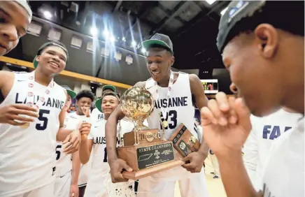  ?? MAX GERSH/THE COMMERCIAL APPEAL ?? Lausanne's Moussa Cisse (23) holds the championsh­ip trophy and MVP plaque Saturday after his team won the Division II-A state title by beating FACS at Lipscomb University's Allen Arena in Nashville.