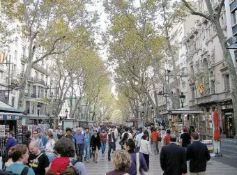  ??  ?? La città-teatro La passeggiat­a di catalani e turisti lungo la Rambla e il viale visto dall’alto