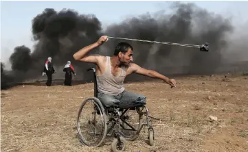  ??  ?? Palestinia­n Saber al-Ashkar, 29, hurls rocks during clashes with Israeli forces along the border with the Gaza strip, east of Gaza City. — AFP photo