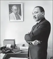  ?? BOB FITCH PHOTOGRAPH­Y ARCHIVE, DEPARTMENT OF SPECIAL COLLECTION­S, STANFORD UNIVERSITY LIBRARIES ?? ■ Dr Martin Luther King, Jr stands next to a portrait of Mahatma Gandhi in his office in 1966.