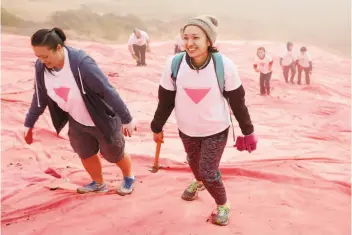  ?? Santiago Mejia / The Chronicle ?? Thao Nguyen (left) and her sister Amy Herbertson climb back up the hill after helping to install the pink triangle on Twin Peaks.