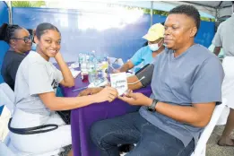  ?? ?? Nurse Aaliyah Cooper (left), presents a Know Your Numbers passport to Jerome Barnaby (right) during the ‘Know Your Numbers’ screening campaign put on by the Ministry of Health and Wellness inside the St William Grant Park in downtown Kingston last Thursday.