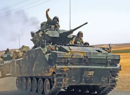  ?? – Reuters ?? CROSS-BORDER OFFENSIVE: A Turkish soldier on an armoured personnel carrier waves as they drive from the border back to their base in Karkamis on the Turkish-Syrian border in the southeaste­rn Gaziantep province, Turkey.