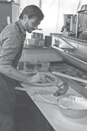  ??  ?? Miles Tamboli prepares pizza in his new restaurant.