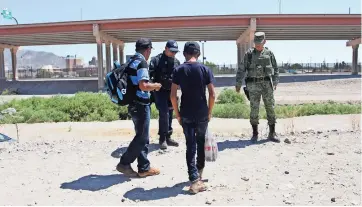  ??  ?? Policías Y militares interrogan a un grupo de extranjero­s en el bordo del río Bravo