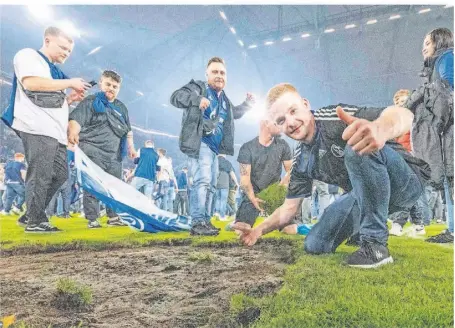  ?? FOTO: DAVID INDERLIED/DPA ?? Tausende Schalker Fans stürmten nach dem Sieg gegen St. Pauli das Feld und feierten den Aufstieg. Viele schnitten sich als Andenken Stücke aus dem Rasen.