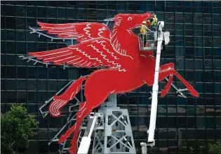  ?? Tom Fox/The Dallas Morning News via AP ?? Starlite Sign installers Brach Daniel, left, and Ray Allen wire the original red Pegasus horse sitting atop a miniature oil derrick May 6 in front of the Omni Dallas. Measuring 42 feet wide and 40 feet high, the restored Pegasus will rise 40 feet...