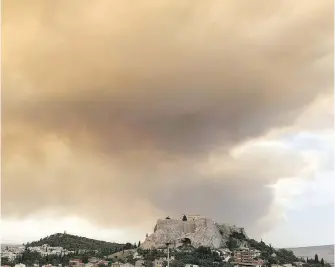  ??  ?? A plume of smoke turns large parts of the sky orange over Athens, including the ancient Acropolis hill, as a forest fire burns in a mountainou­s area west of Athens, sending nearby residents fleeing on Monday.