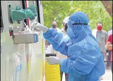  ?? ANI ?? A medical staffer in PPE suit prepares a swab sample collection kit at Police Lines in Gurugram on Monday.