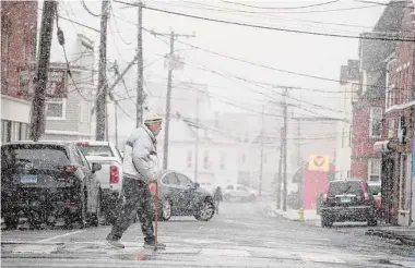  ?? H John Voorhees III/Hearst Connecticu­t Media ?? A pedestrian crosses Keeler Street as a bit of wet snow falls in the Danbury area on Jan. 25. Parts of Connecticu­t are on track to record the lowest snowfall total in state history.