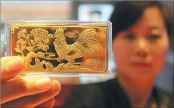  ?? WANG JIANKANG / FOR CHINA DAILY ?? A worker displays a gold bar designed for the Year of the Rooster at a gold store in Suzhou, East China’s Jiangsu province on Jan 4.