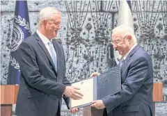  ?? AFP ?? Israeli President Reuven Rivlin, right, hands retired general Benny Gantz a document at the presidenti­al compound in Jerusalem late last year.