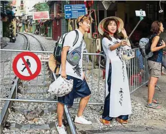  ?? Foto: dpa ?? Zwei Touristen aus Südkorea machen Selfies vor der abgesperrt­en „Train Street“in Hanoi. Offiziell ist die berühmte Trasse seit Jahren für Besucher gesperrt.
