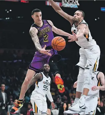  ?? Photograph­s by Wally Skalij Los Angeles Times ?? LONZO BALL passes around Utah’s Rudy Gobert for an assist in the fourth quarter as the Lakers, in their return home, win for the seventh time in eight games. Ball had 10 rebounds and nine points.