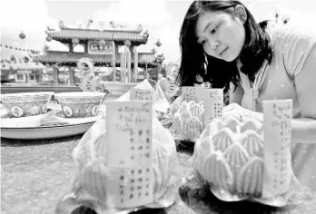  ??  ?? Adel Tan, 37, lighting up lotus-shaped candles during her visit to Lim Fah San Temple at Jalan Tabuan in Kuching. According to traditiona­l Chinese belief, the lotus symbolises good luck or blessing, and is a common feature in Chinese New Year...